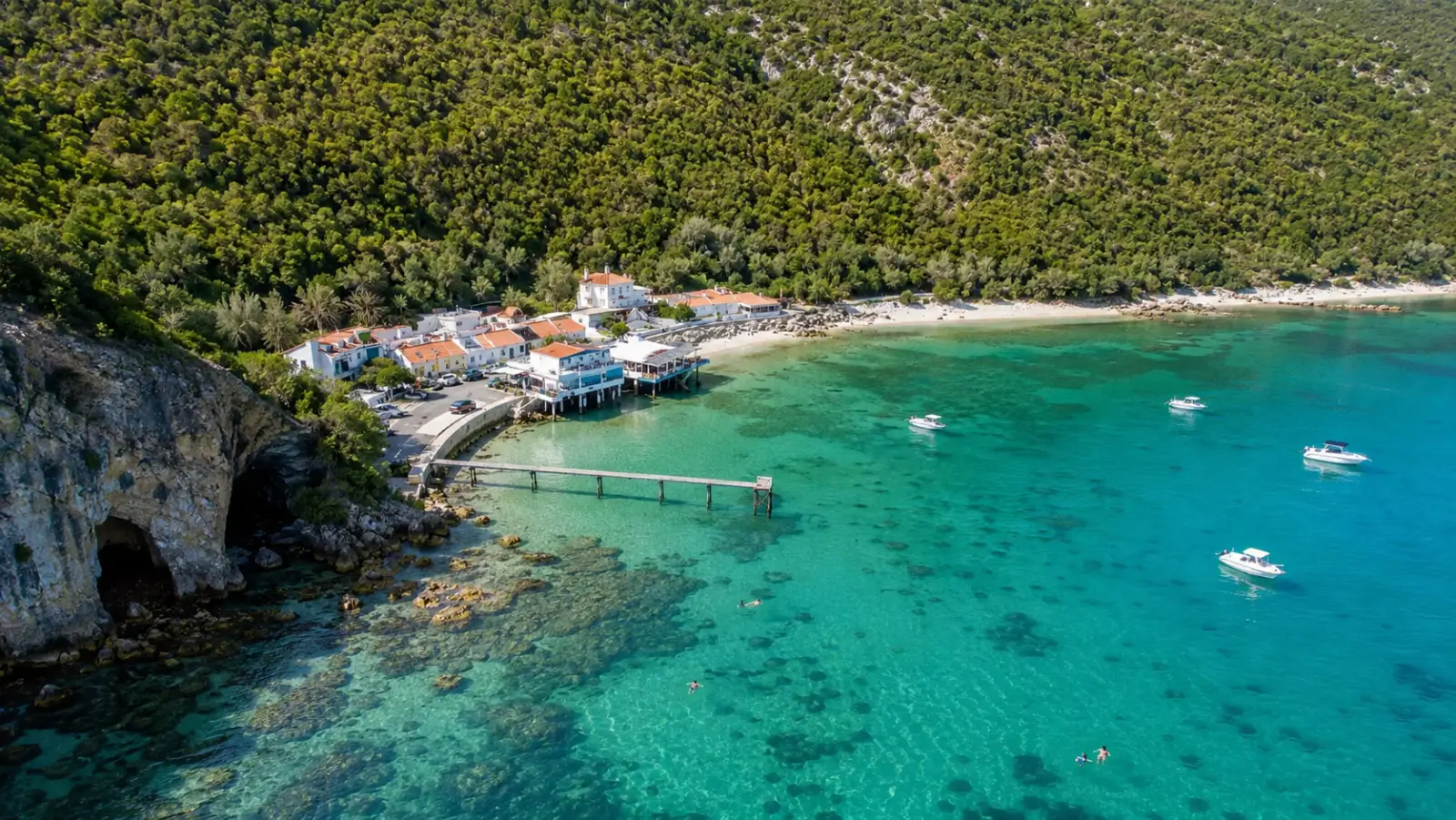 Portinho da Arrábida beach: calm sheltered bay with clear water, boats and a pier