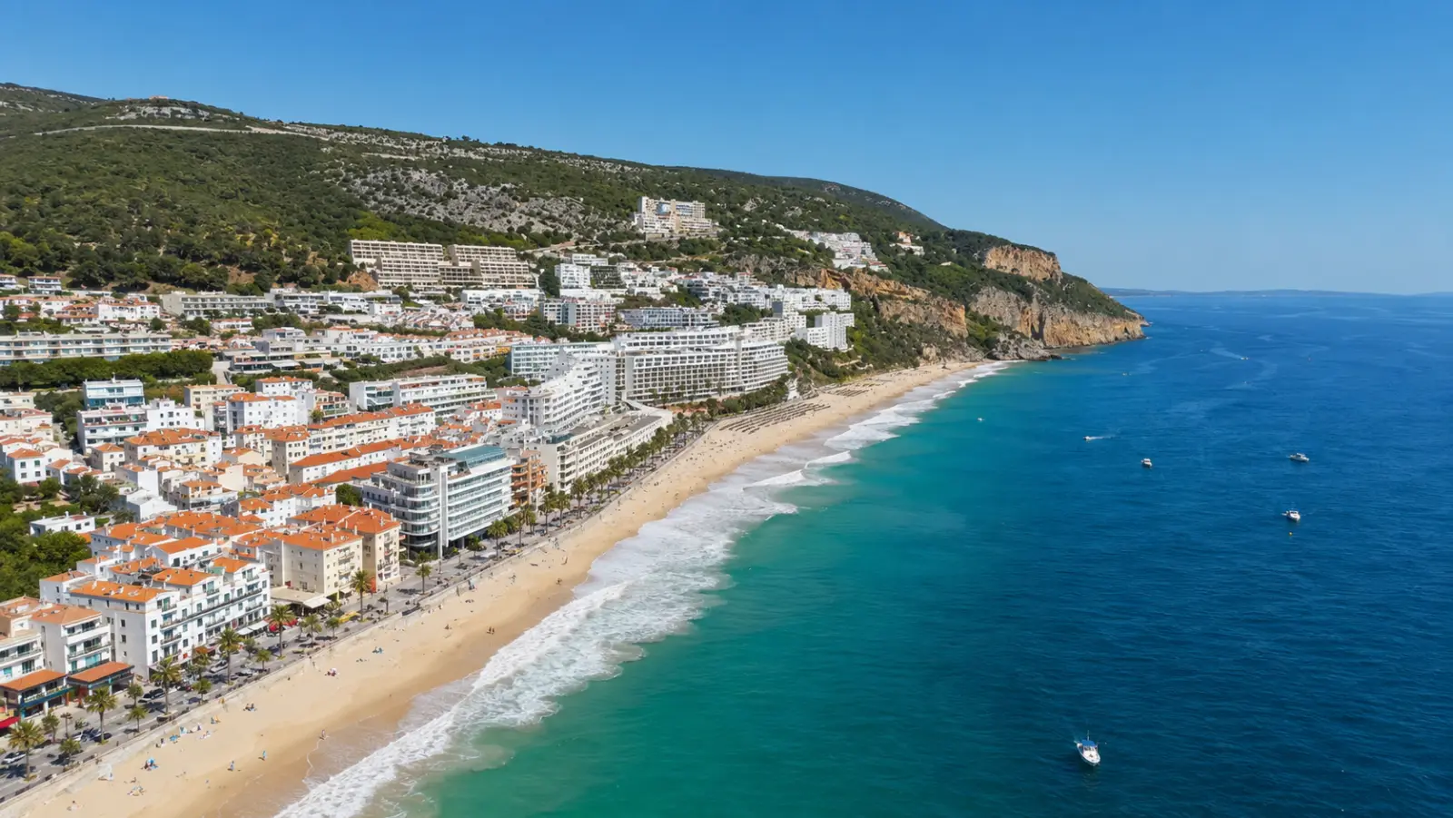 Aerial view of Sesimbra: white town, long sandy beach and turquoise sea under the Arrábida hills