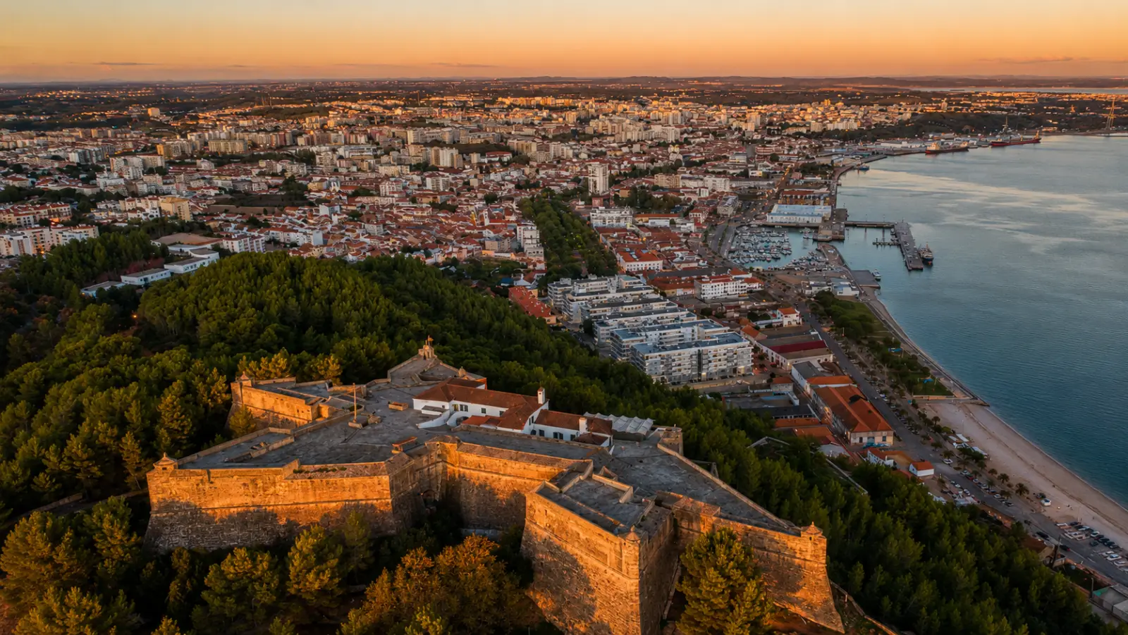 Aerial view of Setúbal at sunset: the Fort of São Filipe in the foreground, the city and Sado estuary port behind